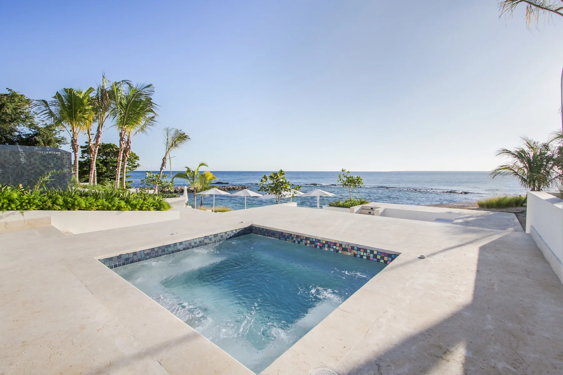 A small pool sits on a paved terrace overlooking the ocean.