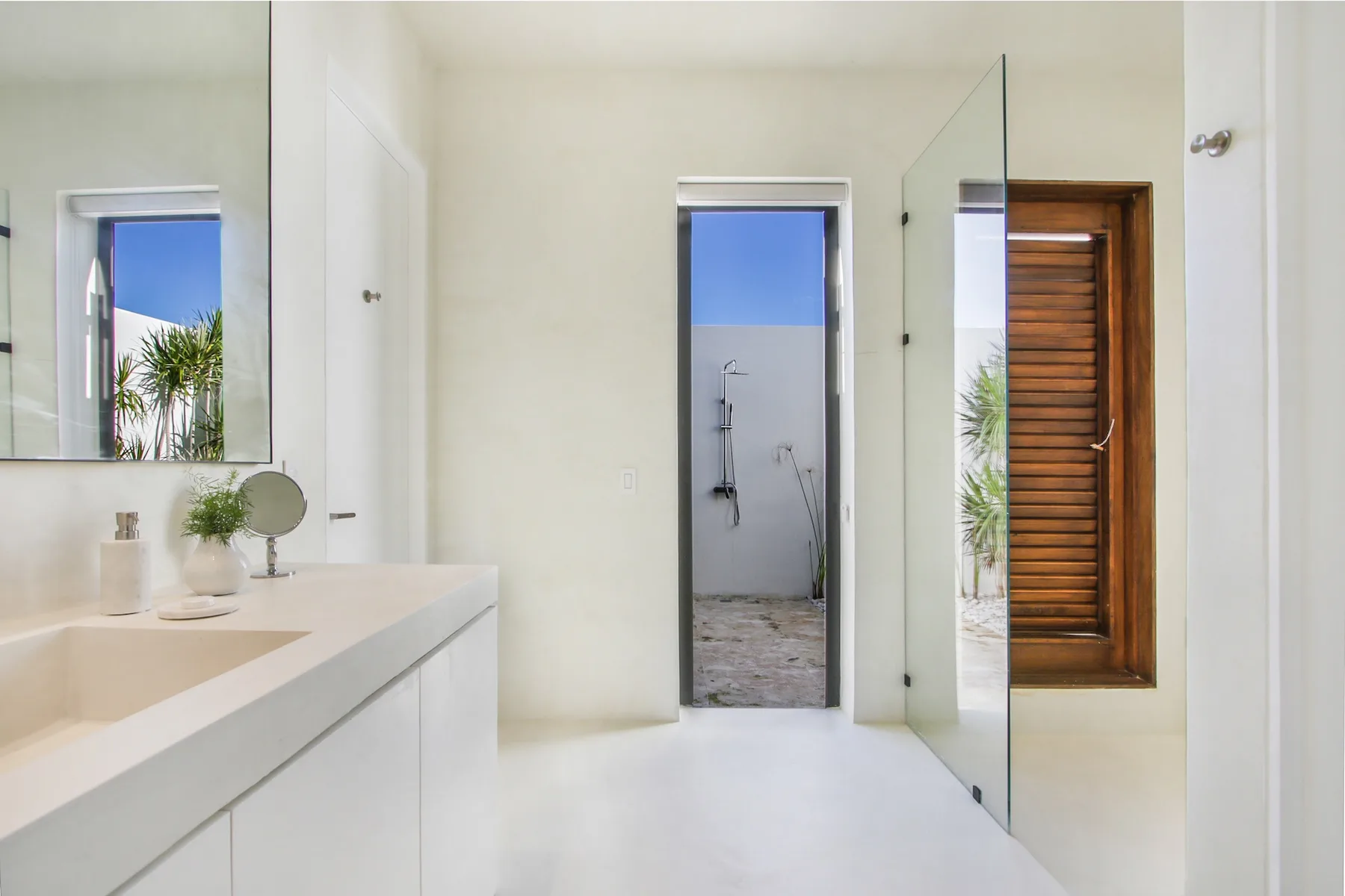 A bright bathroom with a long sink counter and an open shower area.