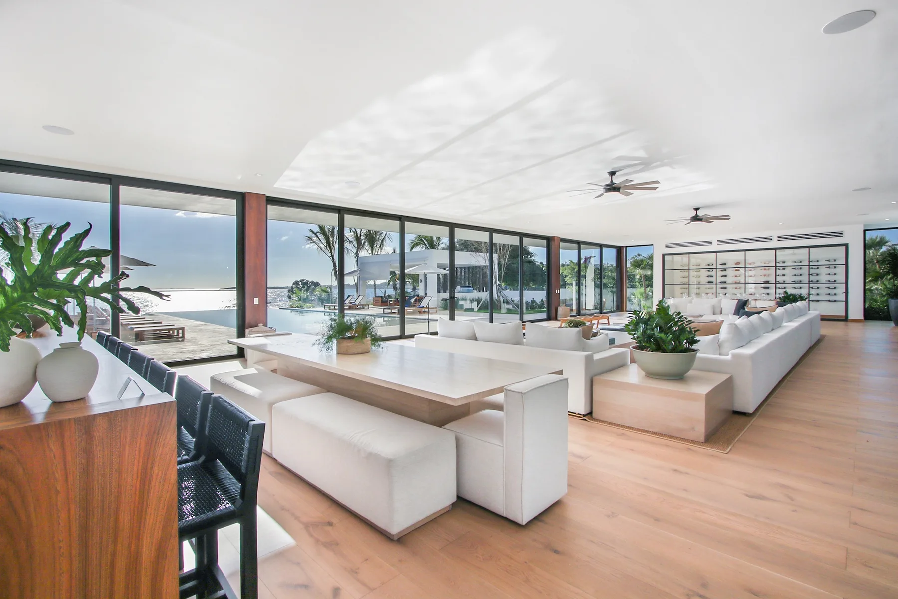 A bright open-plan living and dining area with large windows facing the water.