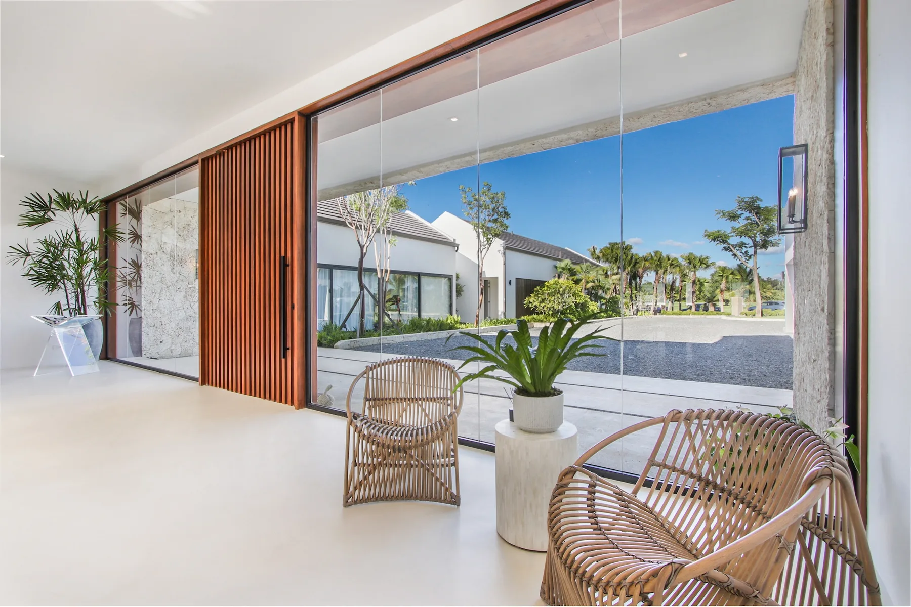 A bright lounge with woven seating beside large glass doors overlooking a landscaped courtyard.