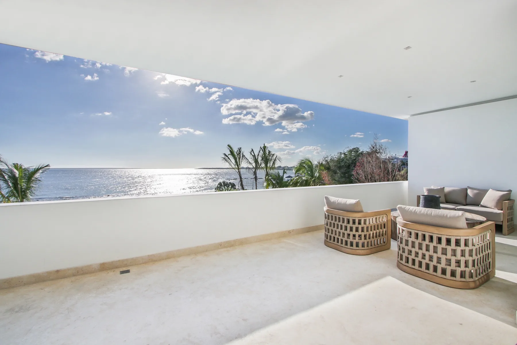 A covered terrace with cushioned seating overlooks the ocean.
