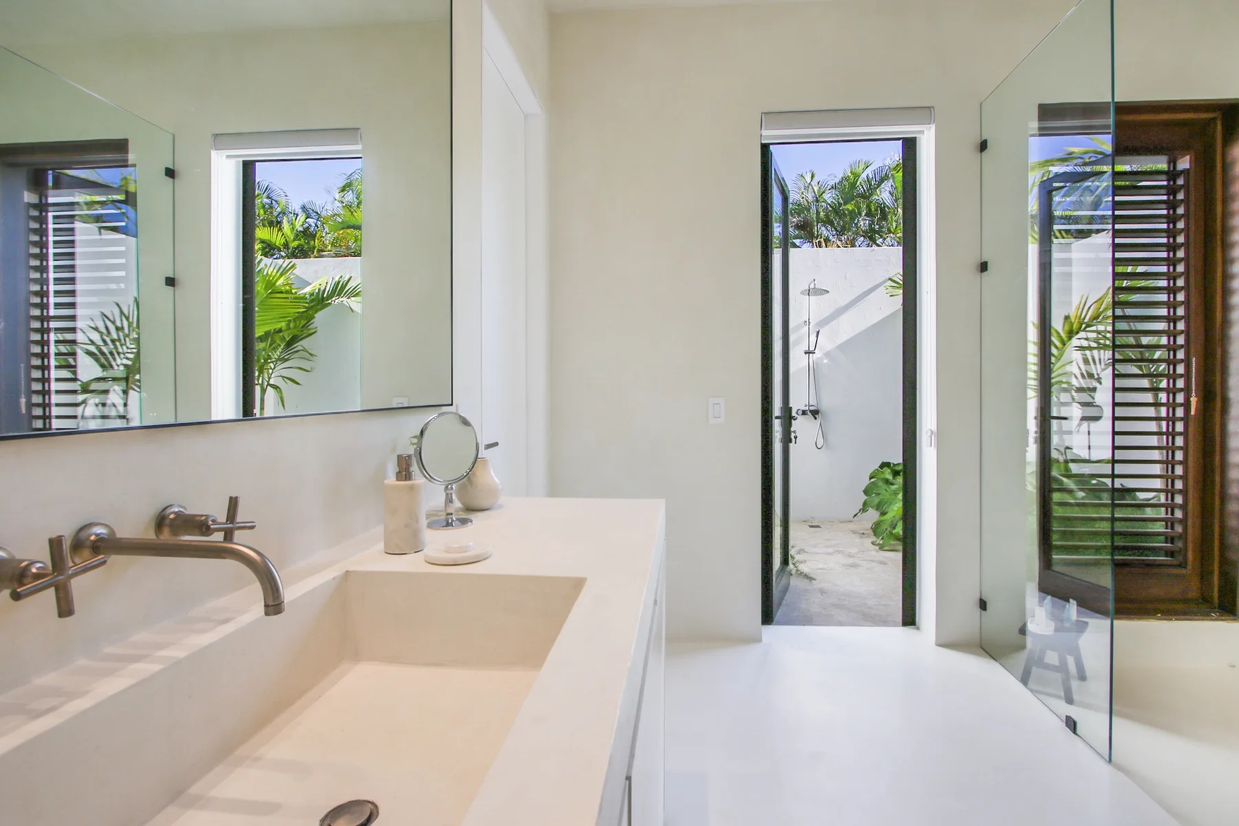 A bright bathroom with a long vanity and an open shower area.