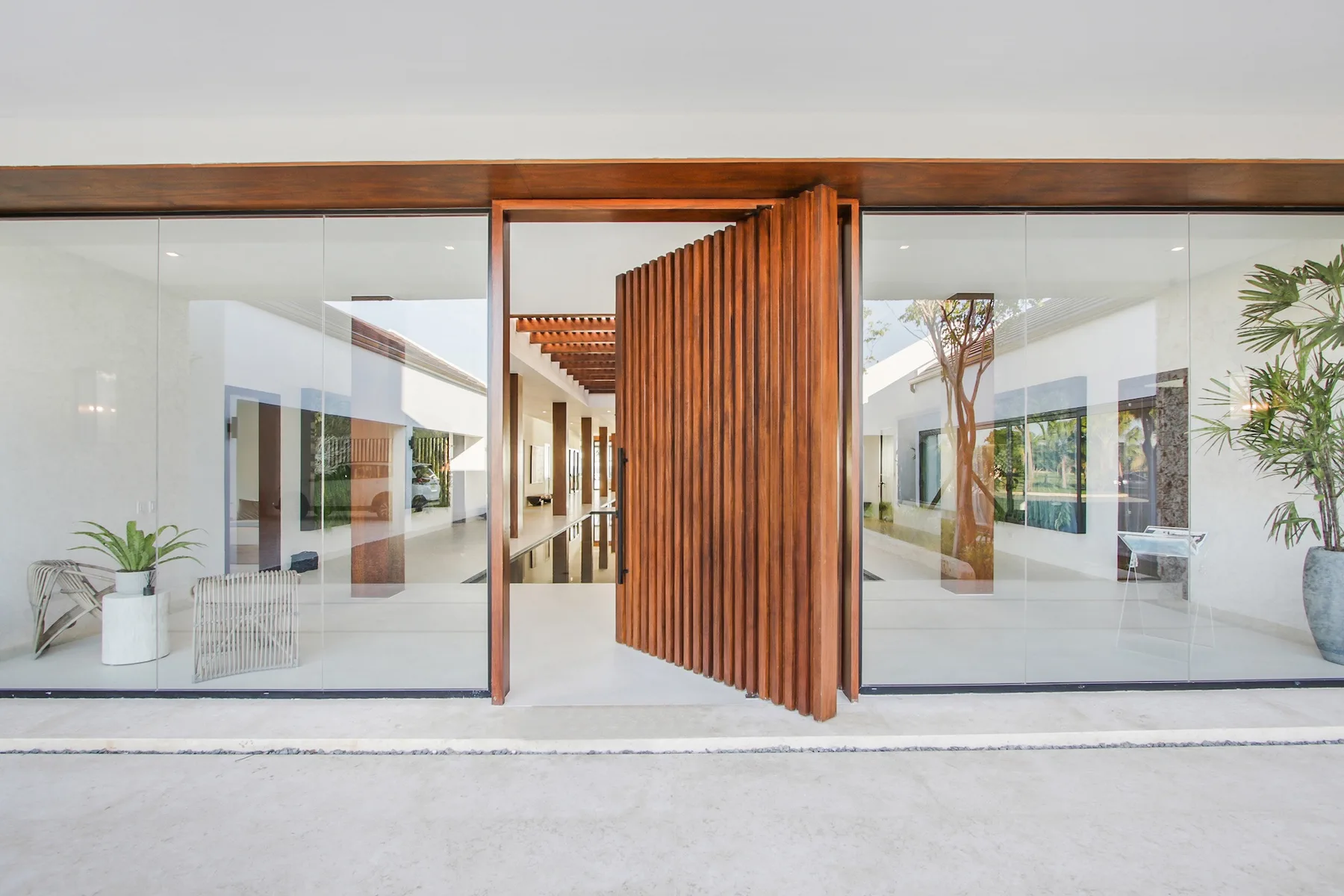 A modern building entrance with glass walls and a wooden slatted door.