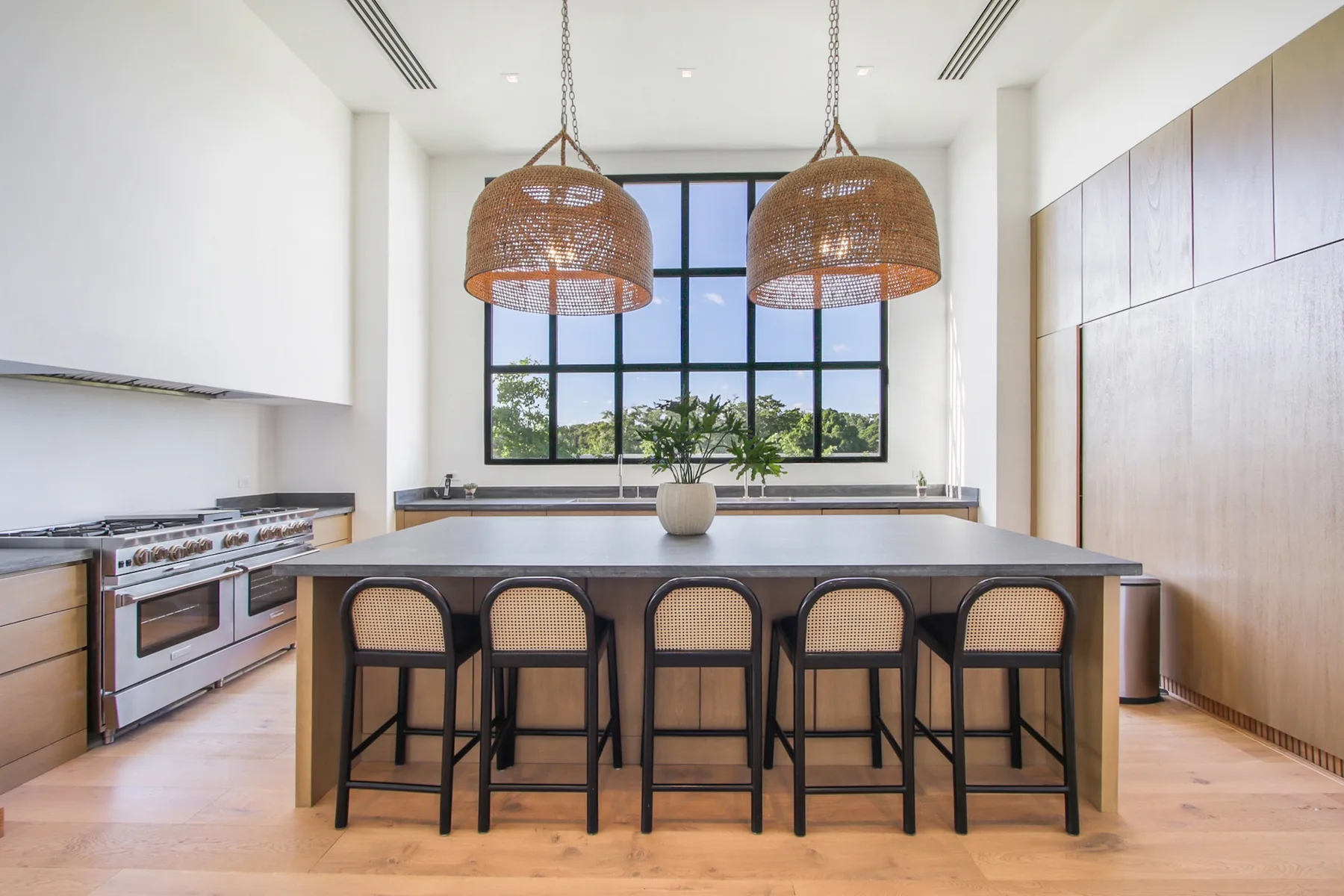 A bright kitchen with a large island, bar seating, and pendant lights.