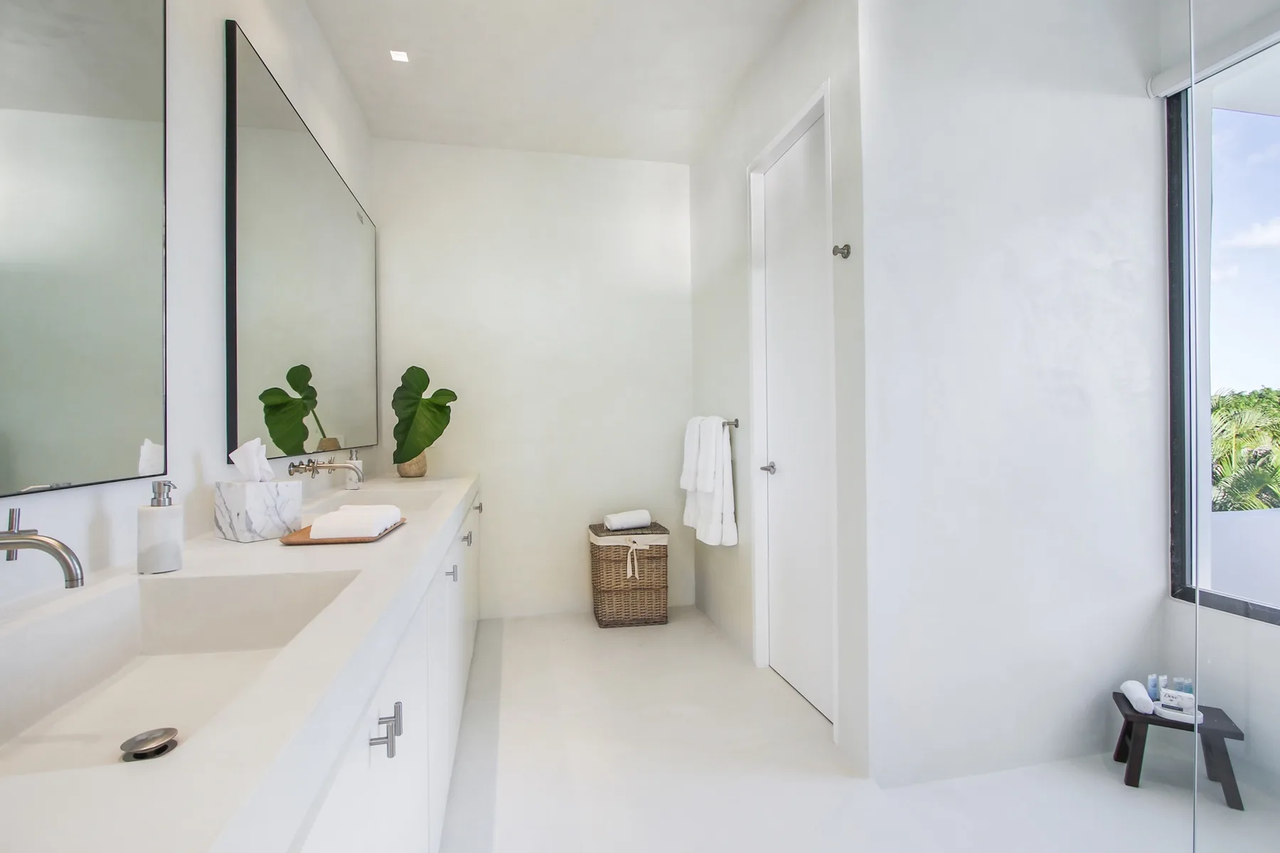 A bright bathroom with a long sink counter and a large wall mirror.