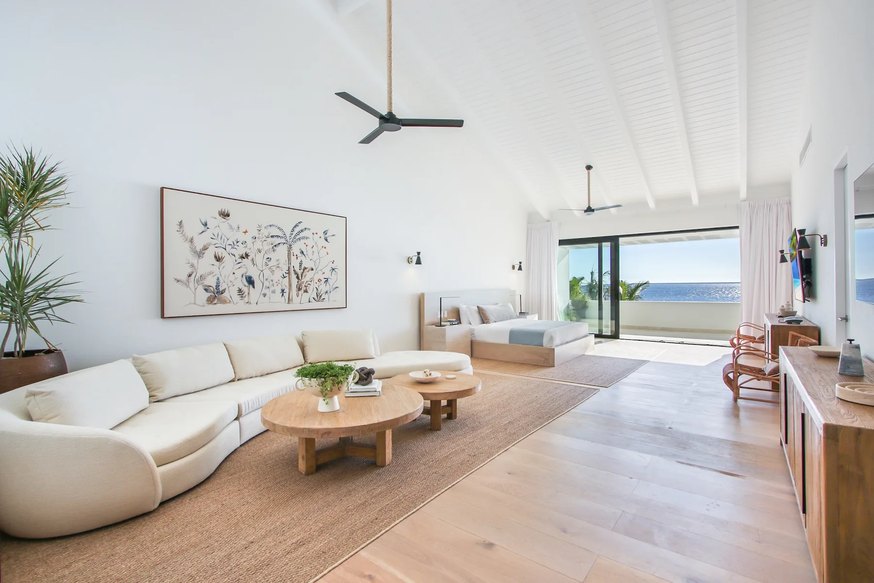 A bright living room with a long seating area and wide ocean-facing windows.