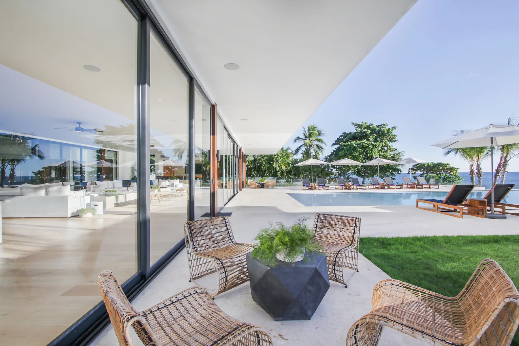 A patio seating area overlooks a swimming pool beside a glass-walled building.