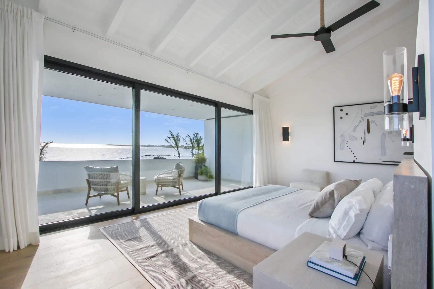 A bright bedroom opens onto a terrace through wide glass doors.