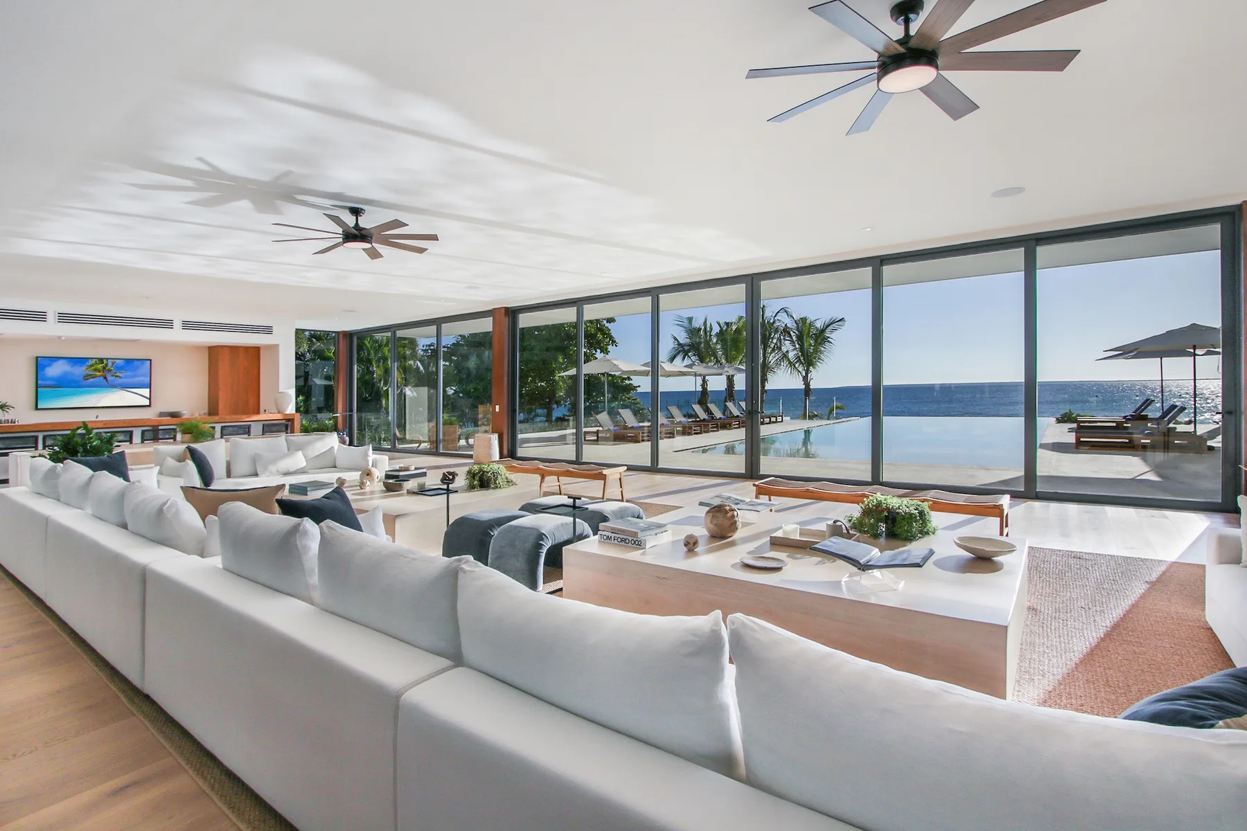 A bright living room with seating and large windows overlooking the ocean.
