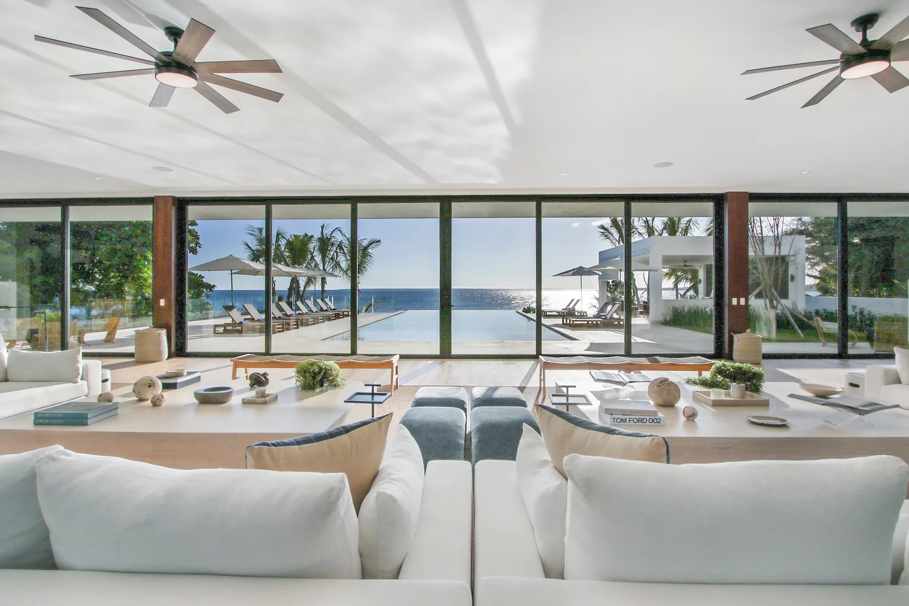 A bright living room with seating facing wide windows and a poolside view.