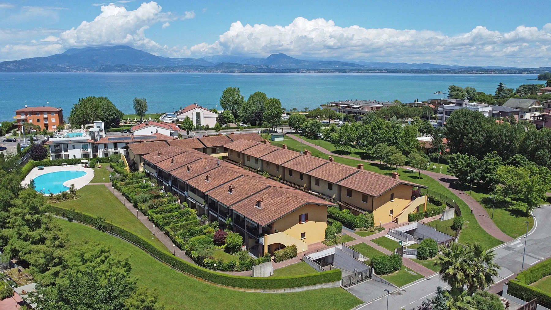 Aerial view of a lakeside residential complex with red-tiled roofs and gardens.
