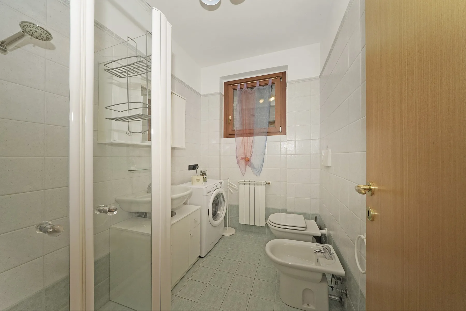 A tiled bathroom with a shower, sink, and toilet.