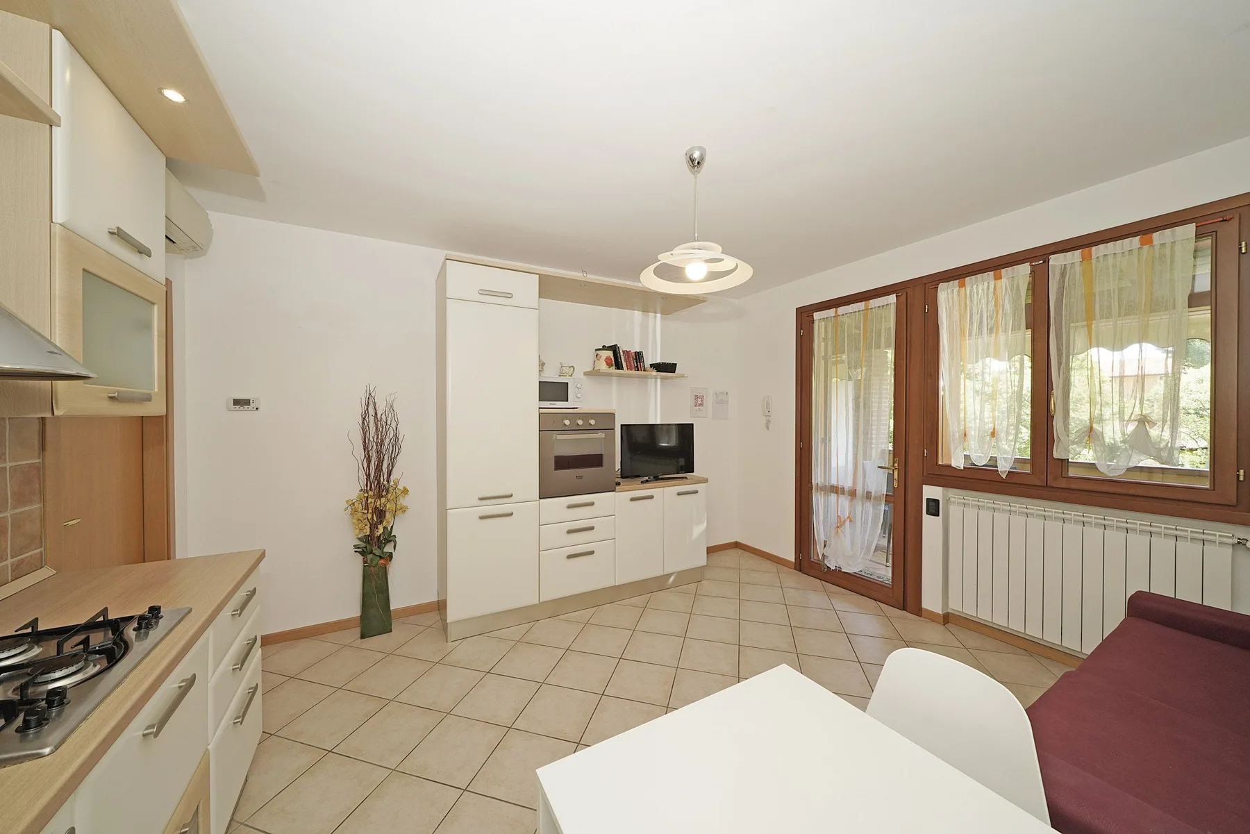 A bright kitchen and dining area with white cabinets and large windows.