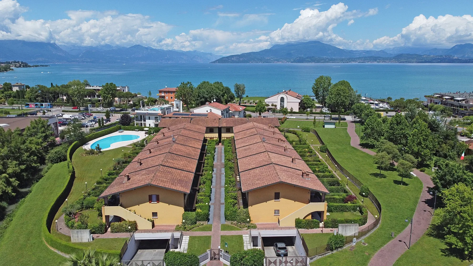 Aerial view of two long buildings and landscaped grounds beside a lake.