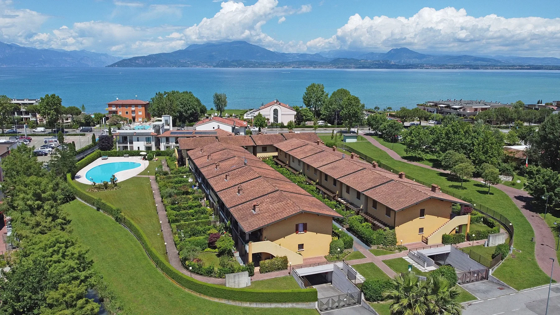 Aerial view of a resort complex beside a lake, with mountains in the distance.