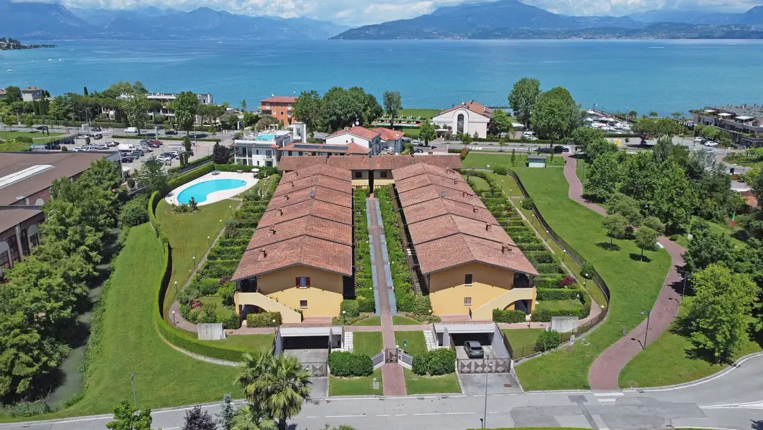 An aerial view of low buildings and landscaped grounds beside a lake.