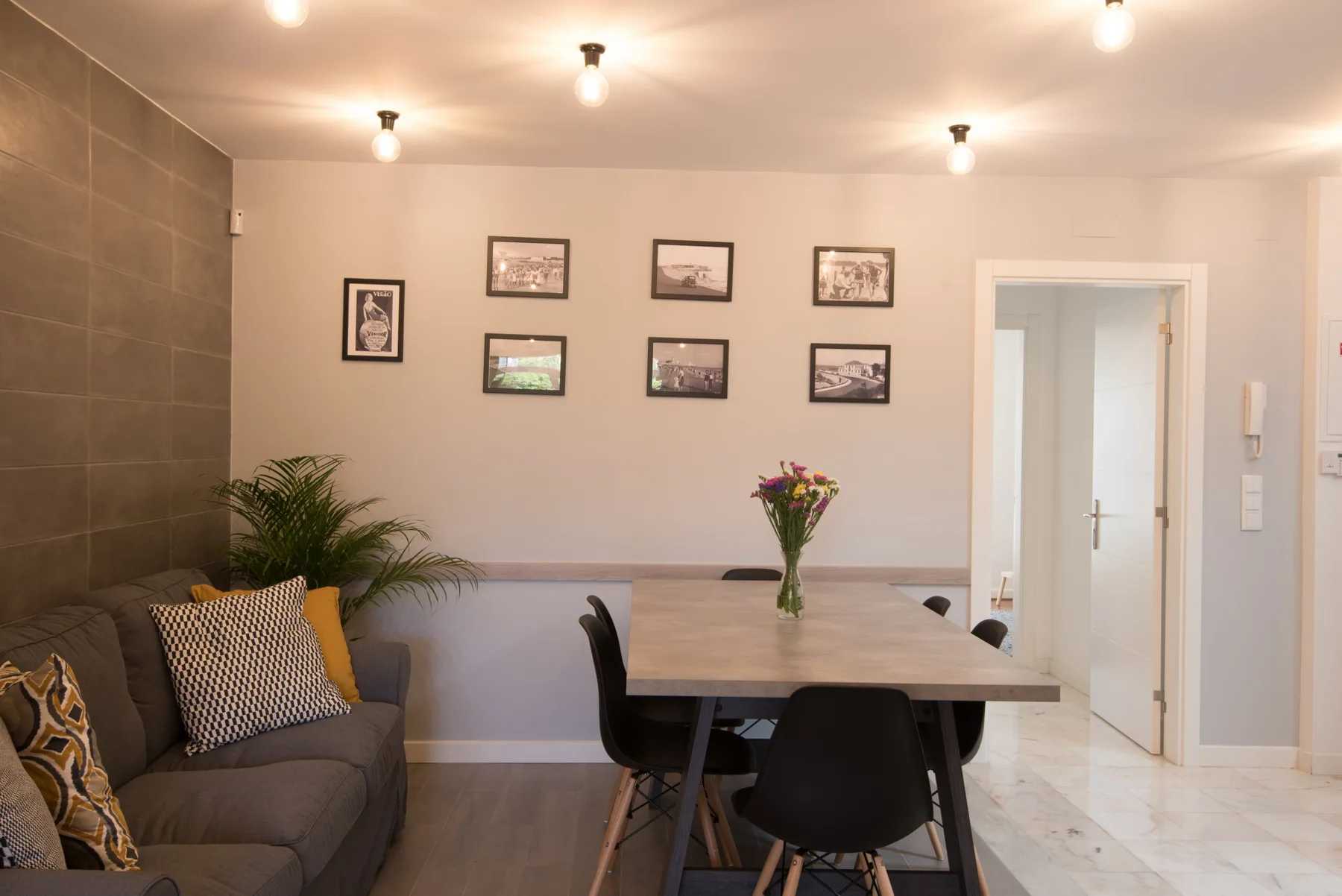 Sala de estar y comedor con un sofá, una mesa y cuadros en la pared.