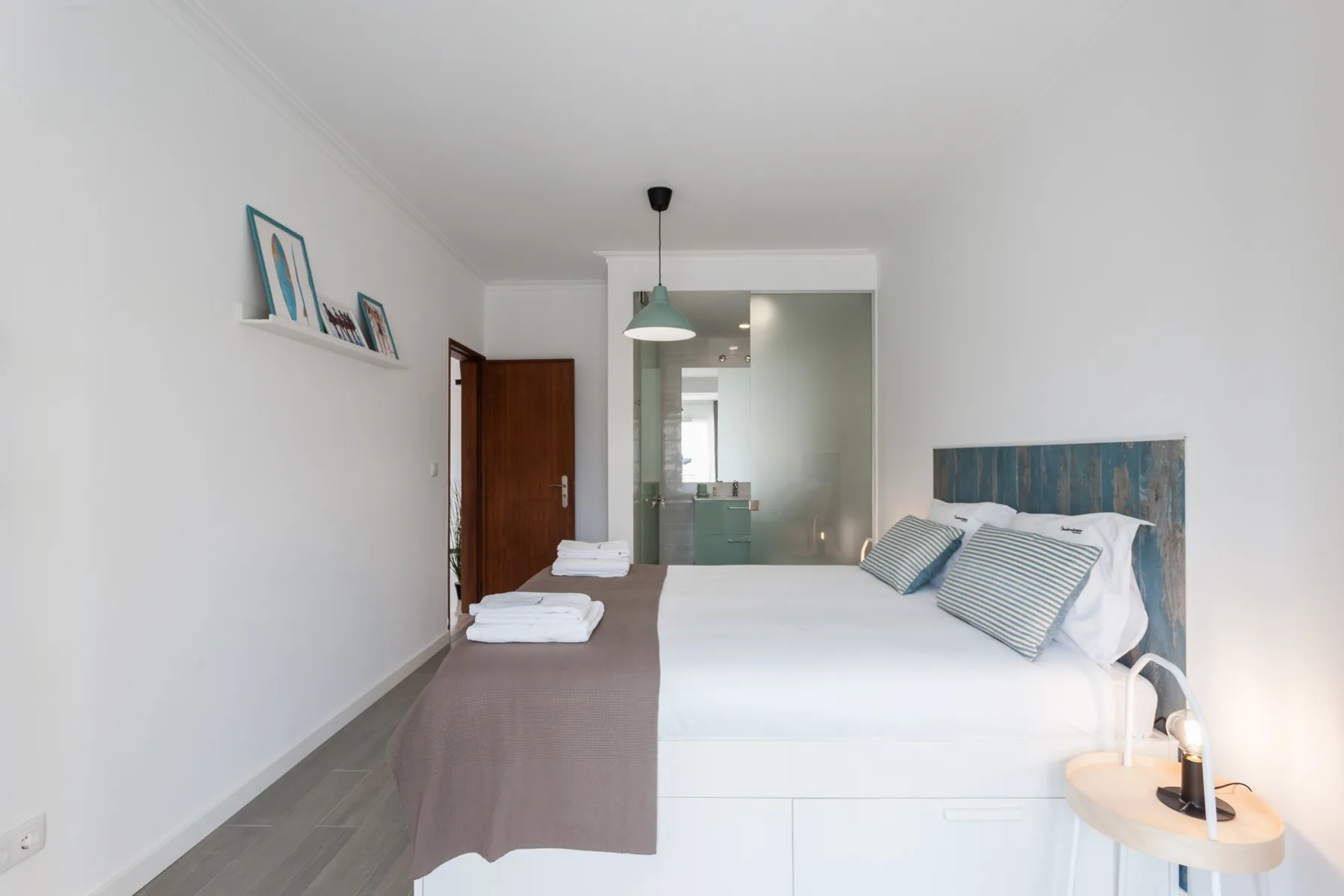 Un dormitorio luminoso con una cama bien hecha y una puerta abierta al baño.