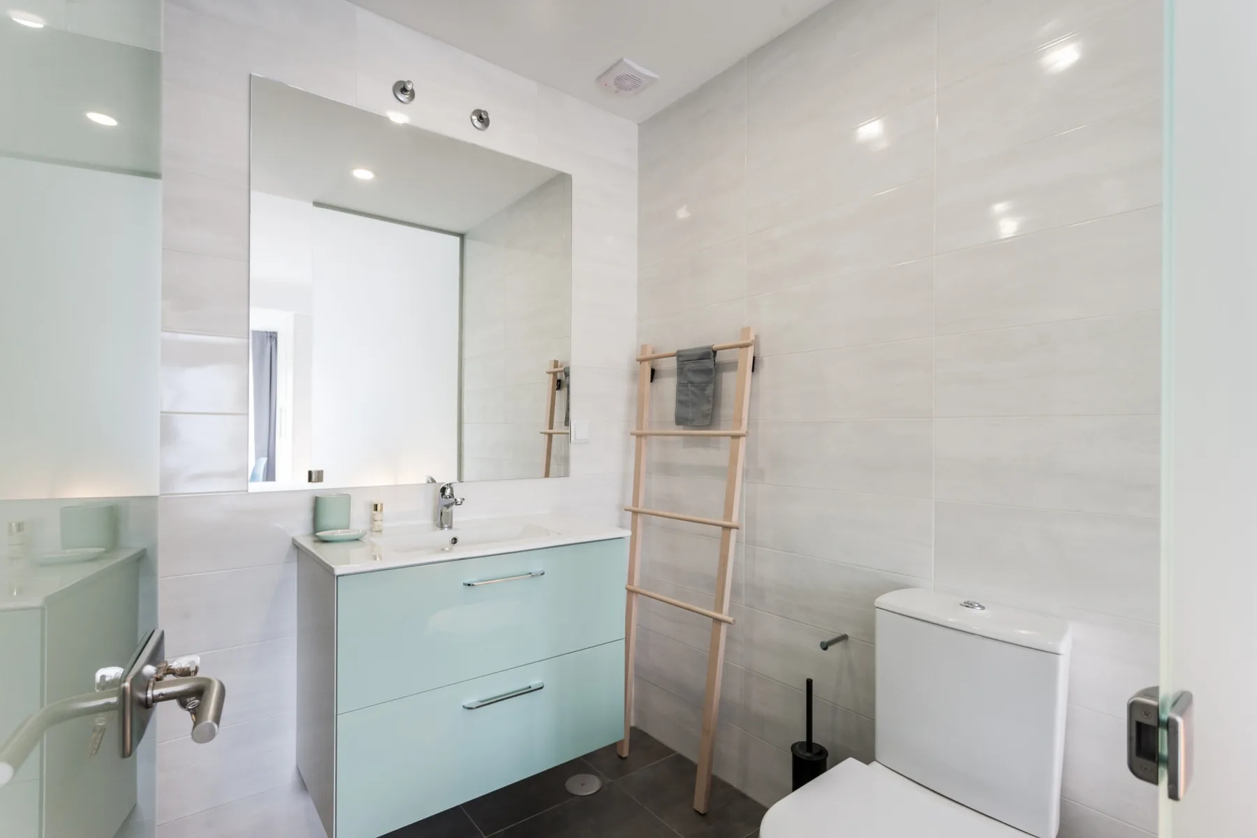 Un baño luminoso tiene un lavabo, un espejo y un inodoro.