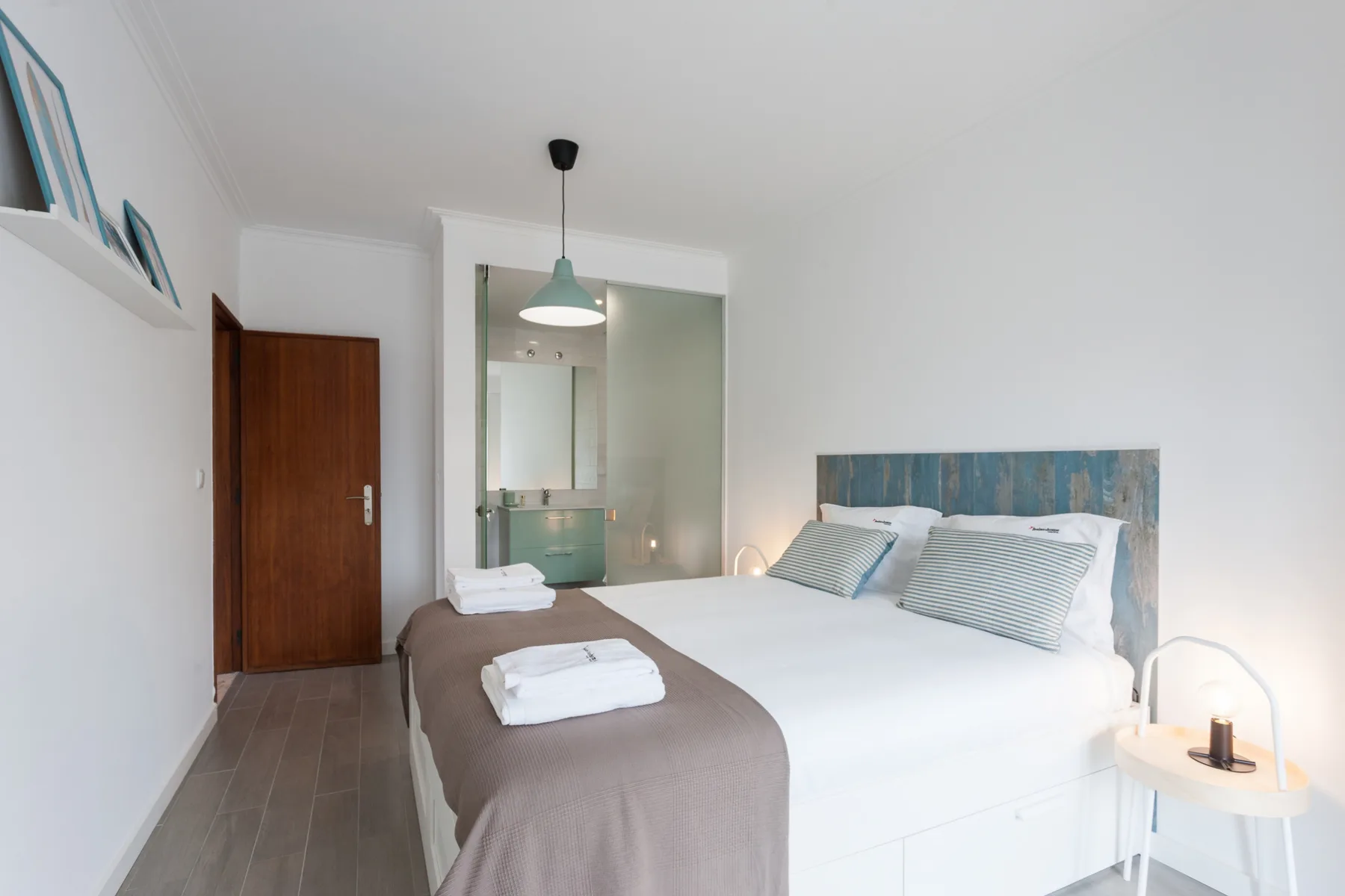 Un dormitorio luminoso con una cama bien hecha y toallas dobladas.