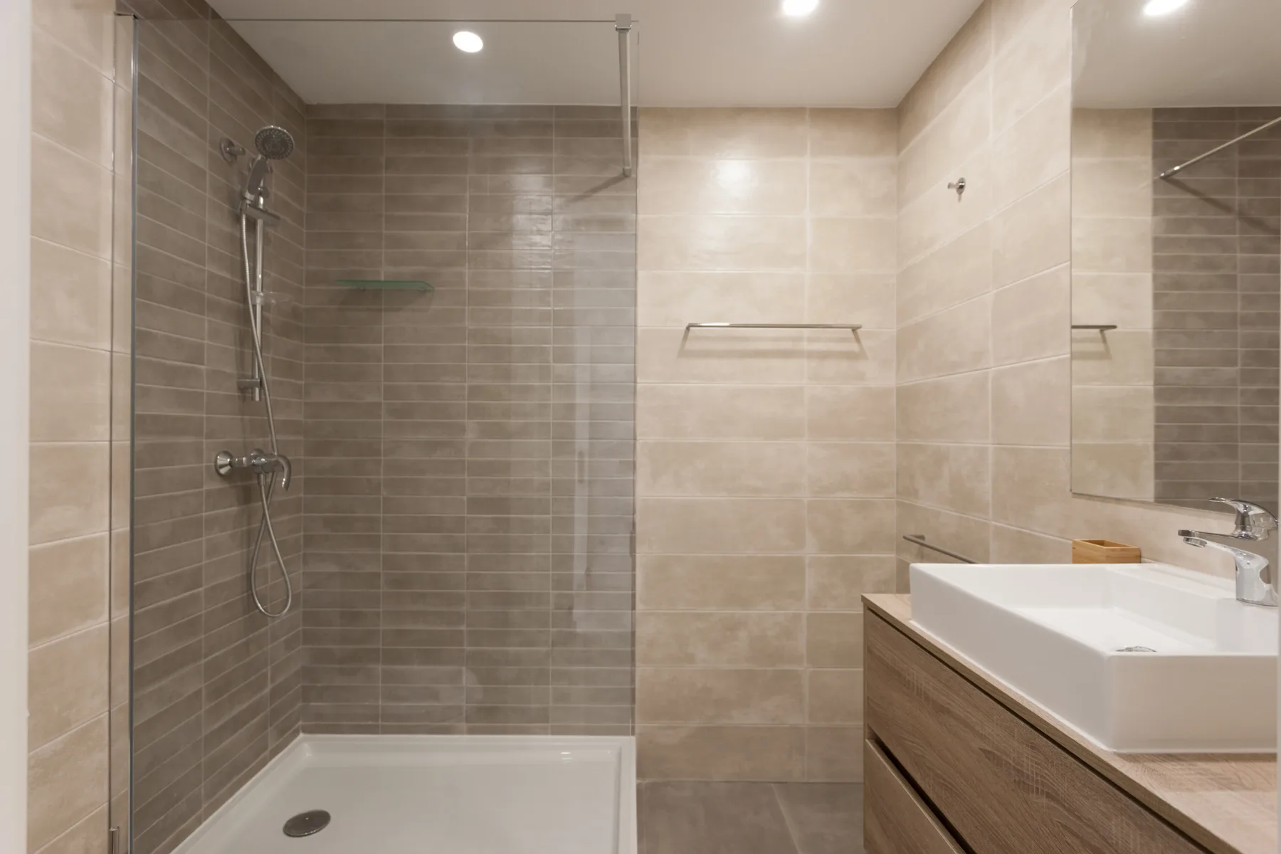 Baño alicatado con ducha y mueble con lavabo.