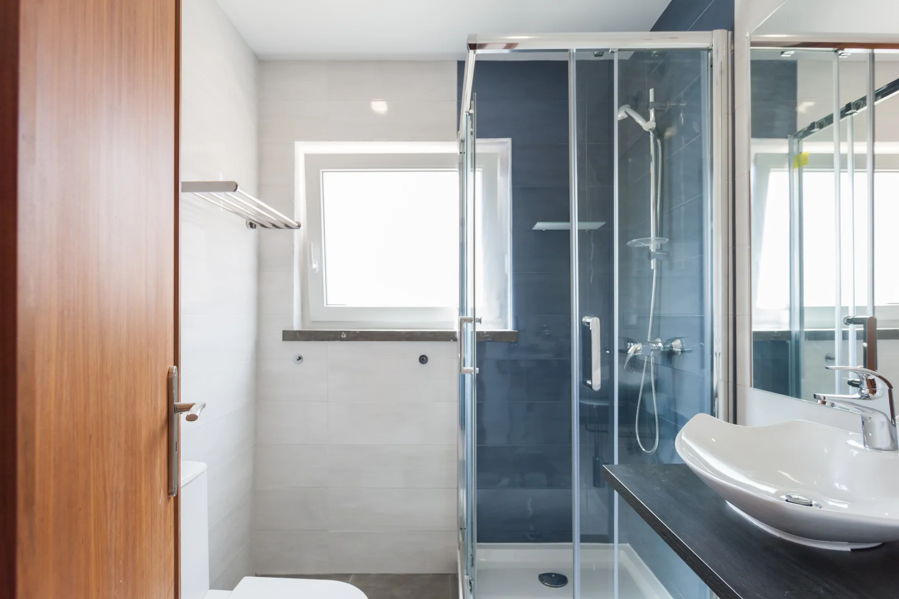 Un baño con una ducha de vidrio y un lavabo blanco.