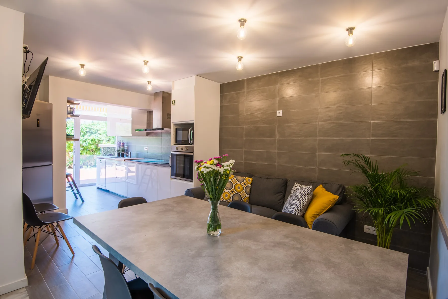 Una zona de comedor se abre a la cocina y la sala de estar, con una mesa grande delante.