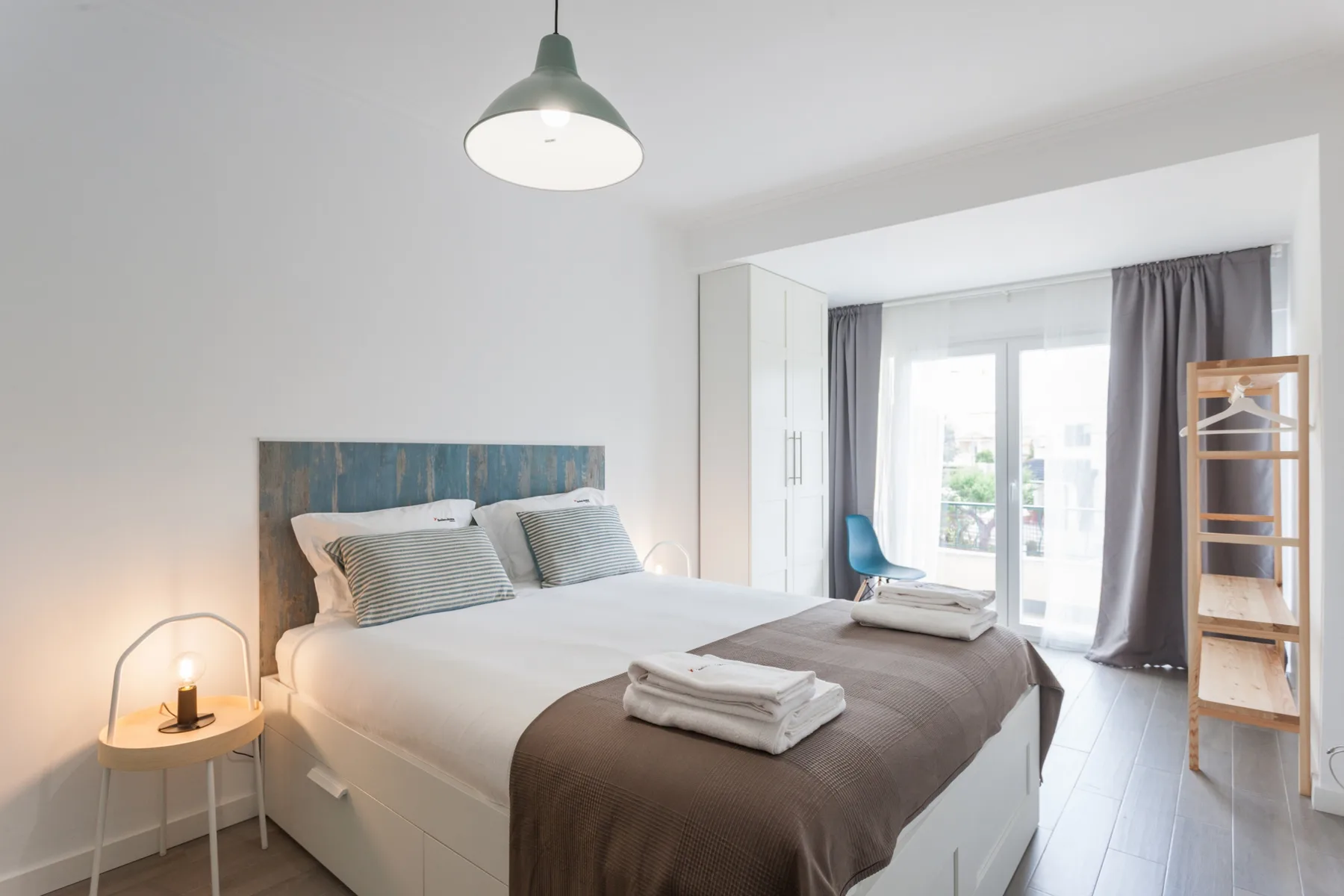Un dormitorio luminoso con una cama bien hecha y grandes ventanas.