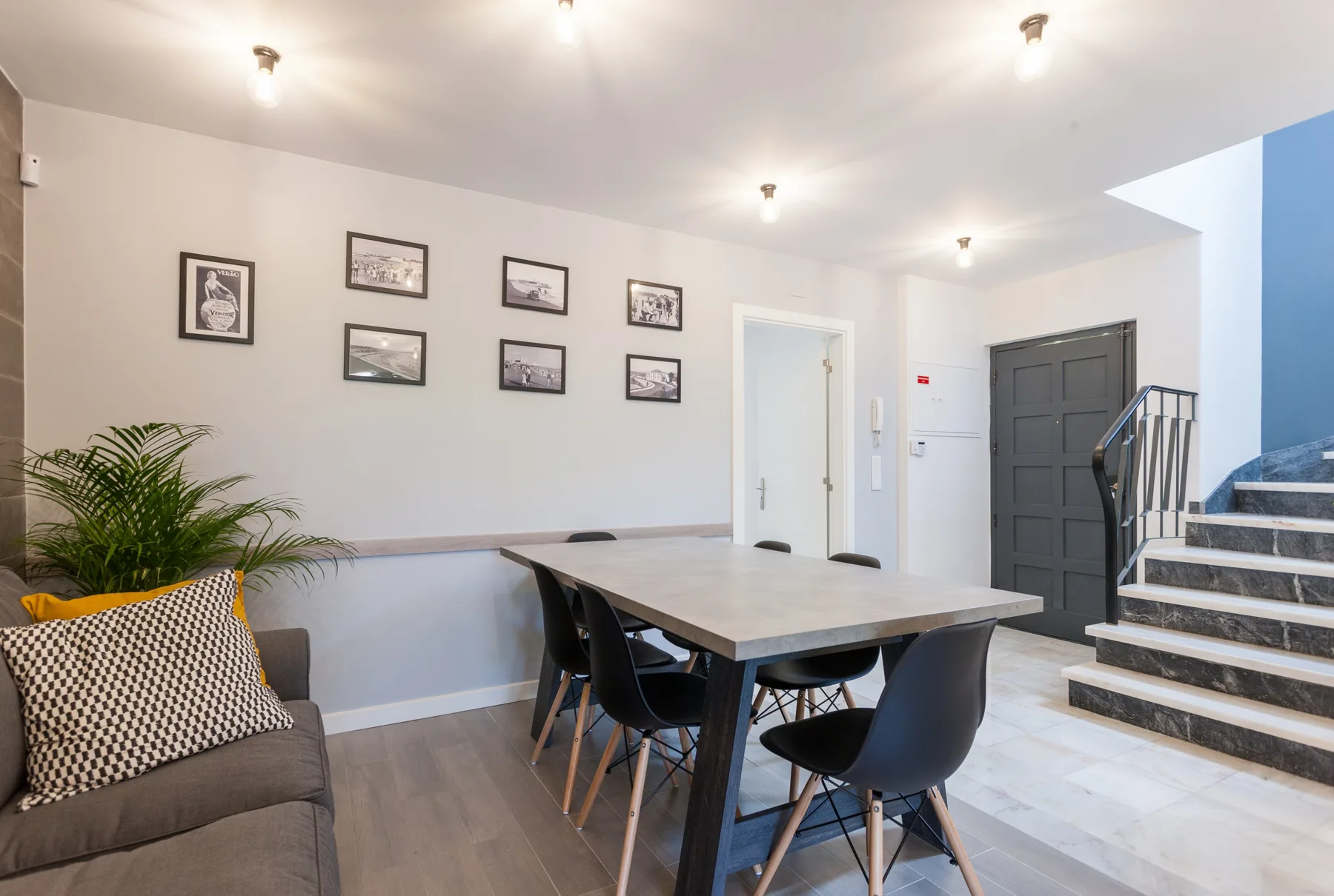 Comedor con una mesa y asientos junto a una zona de estar y una escalera.