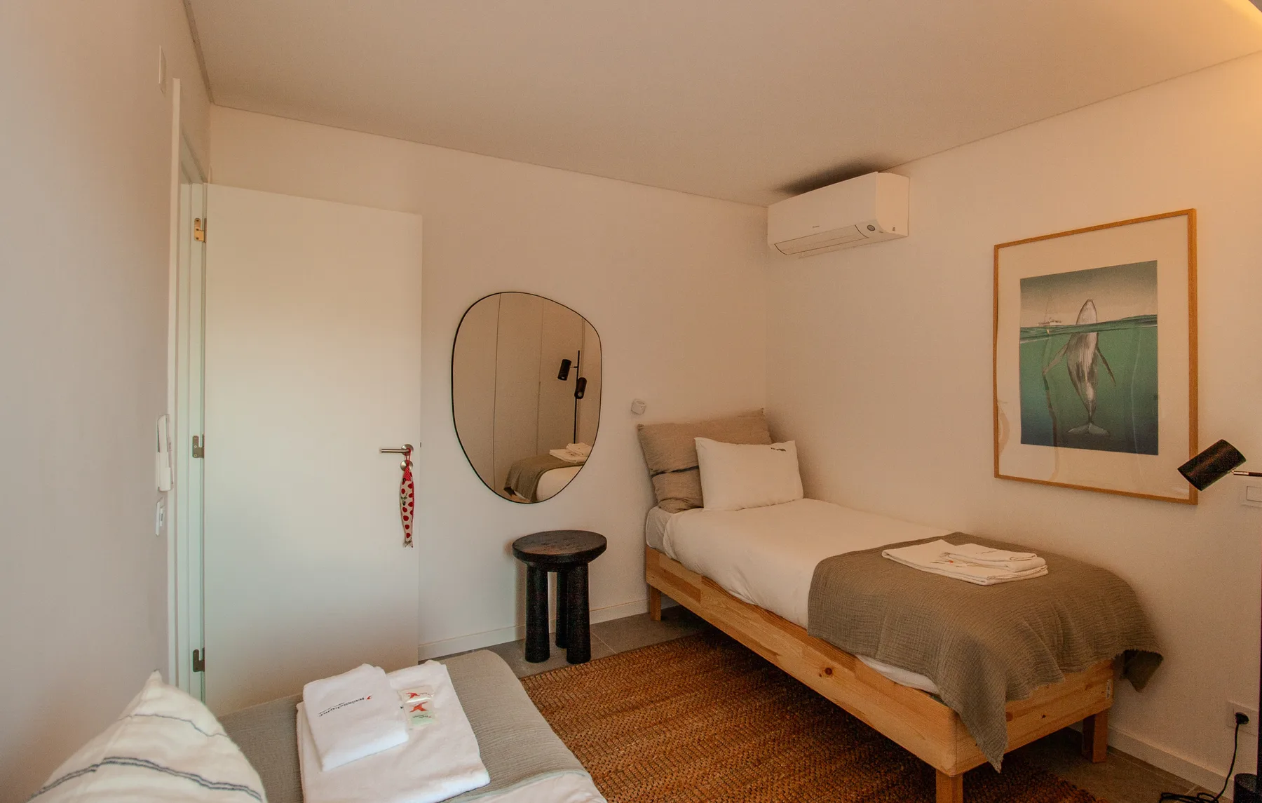 A bedroom with a bed, framed artwork, and a round wall mirror.