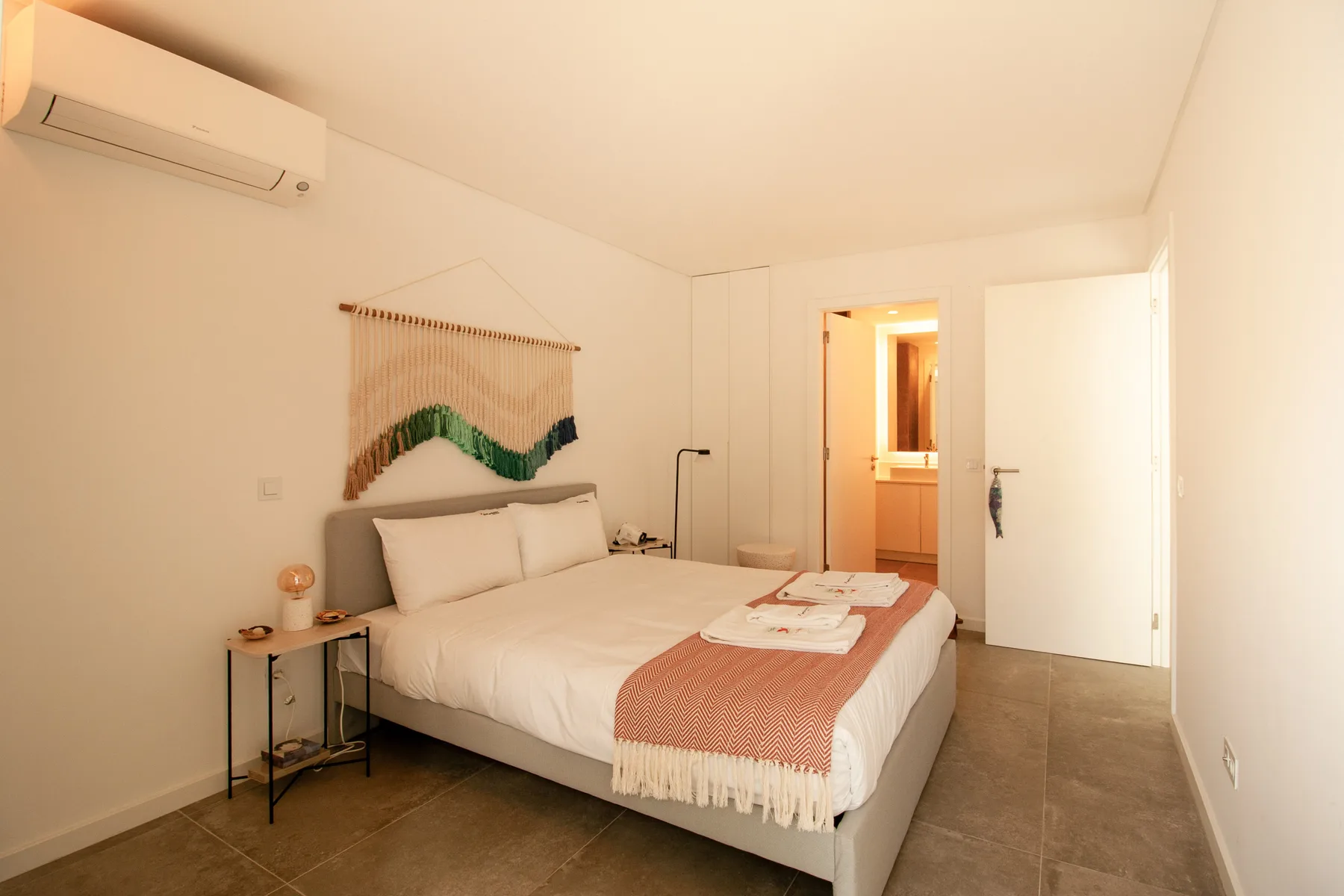 A bedroom with a neatly made bed and an open doorway.