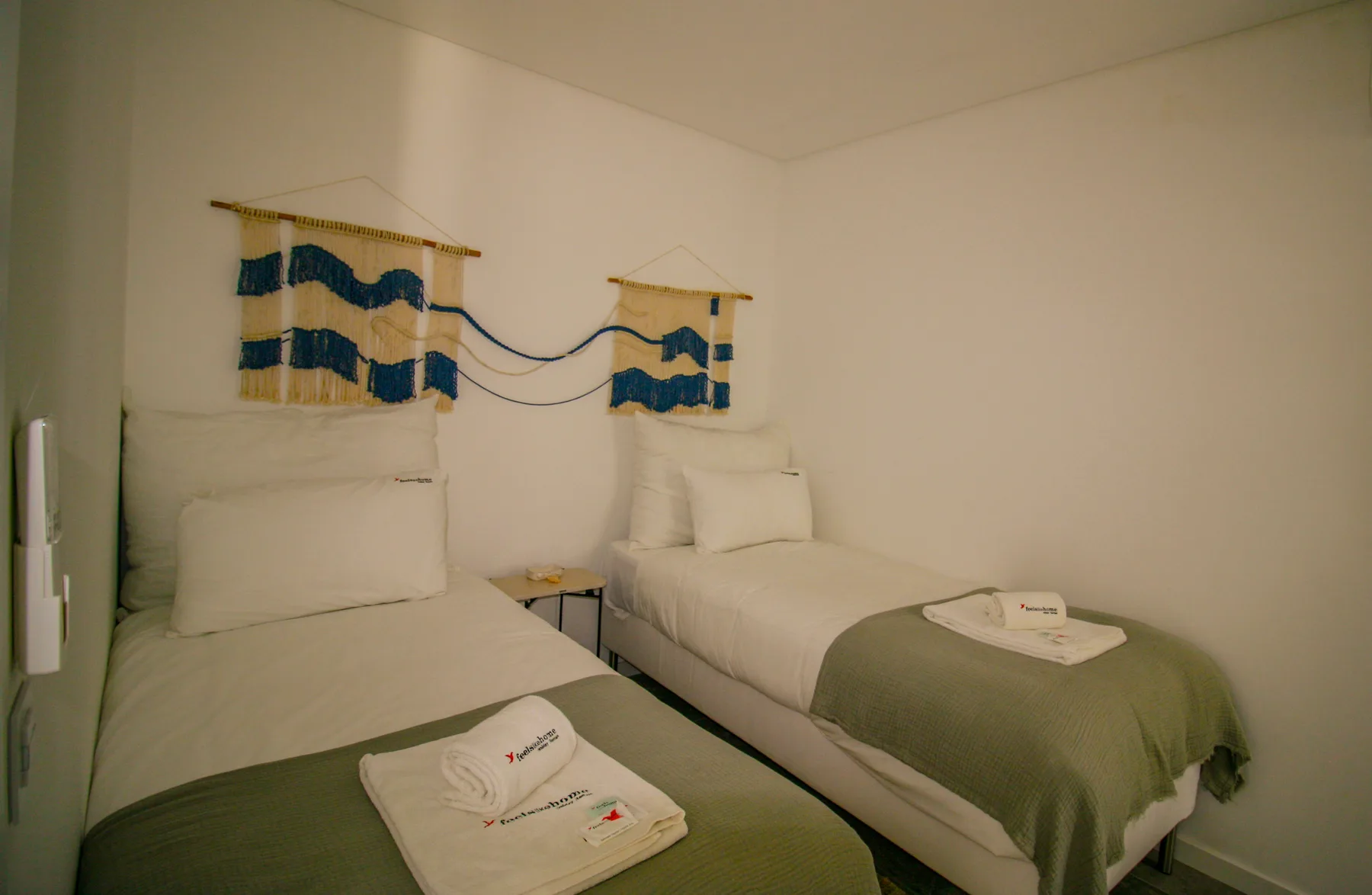 A bedroom with two beds and blue-and-tan wall hangings.