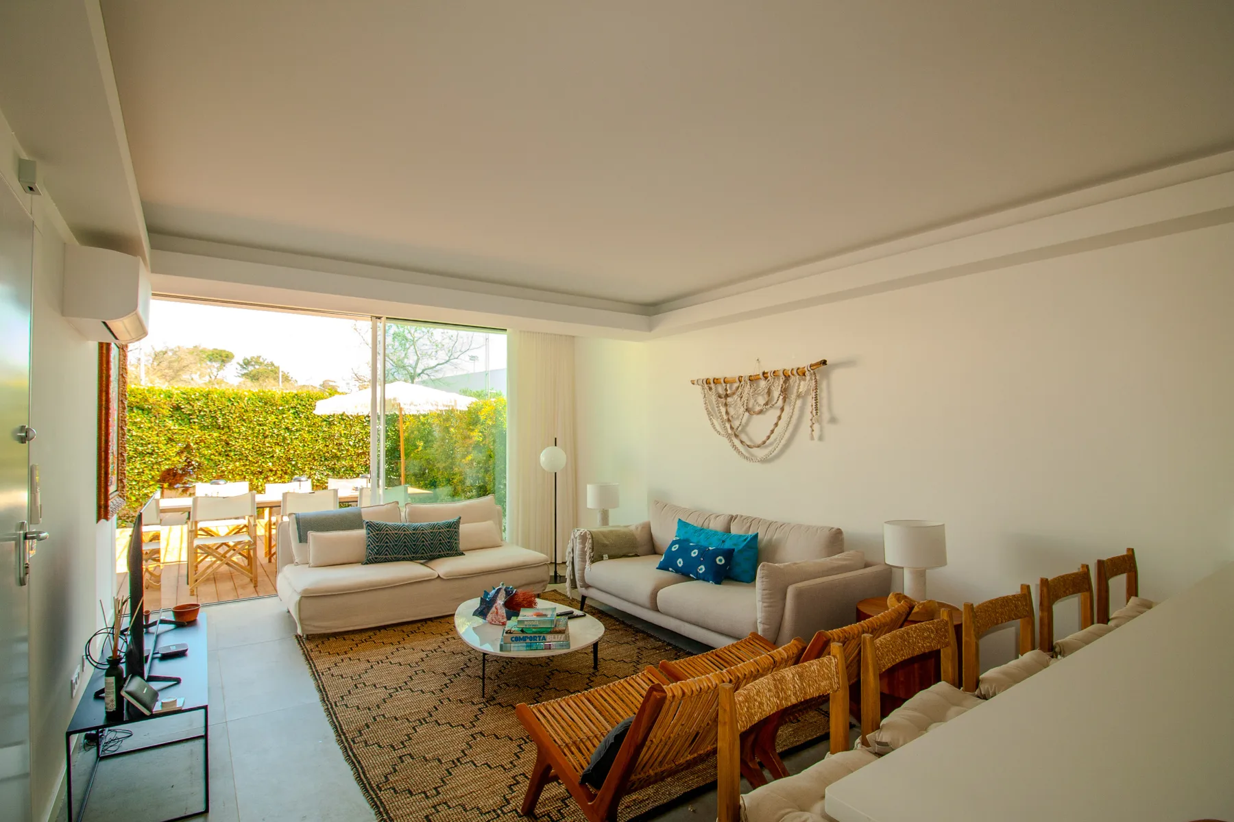 A bright living and dining area opens onto a terrace, with seating and a dining table.