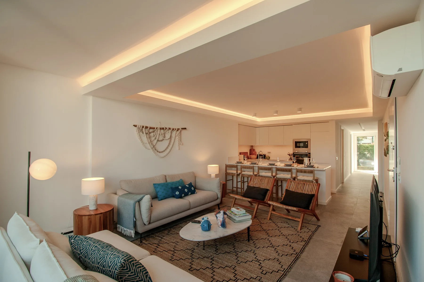 A bright living room with seating, a coffee table, and an open kitchen.