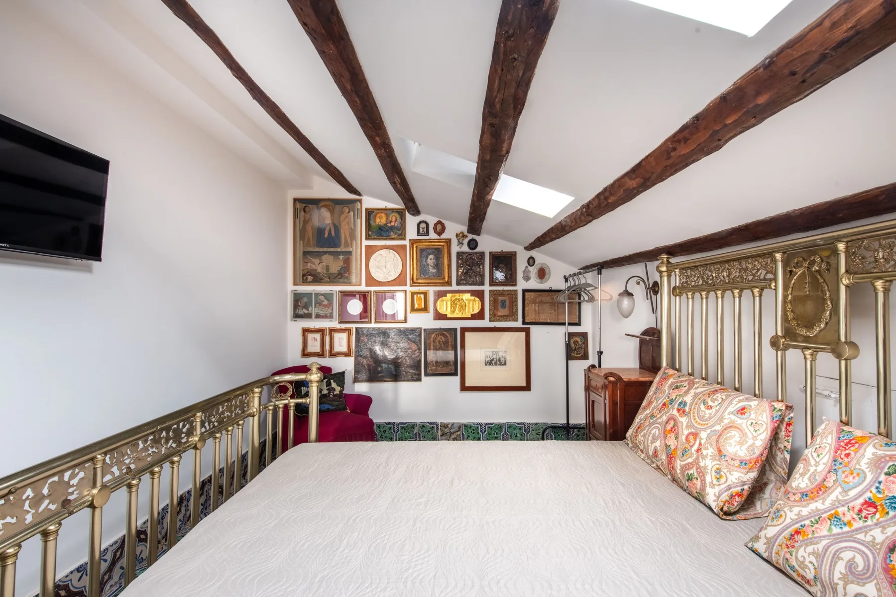 Un dormitorio con una cama grande, cojines estampados y vigas de madera a la vista.