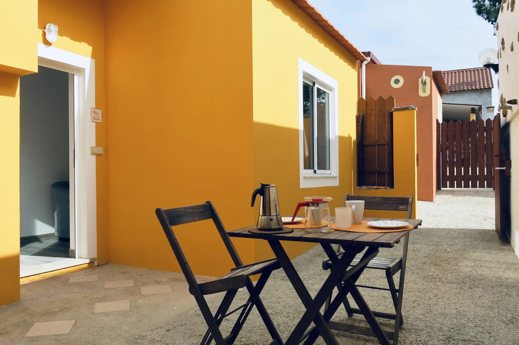 An outdoor patio with a table and seating beside an orange house.