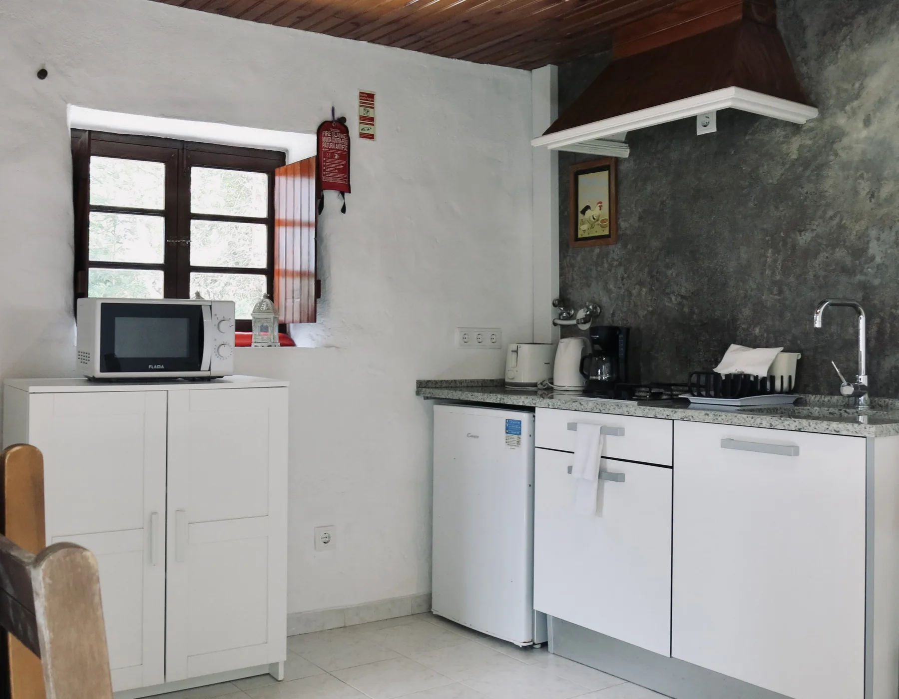 A compact kitchen with white cabinets, a countertop, and a window.
