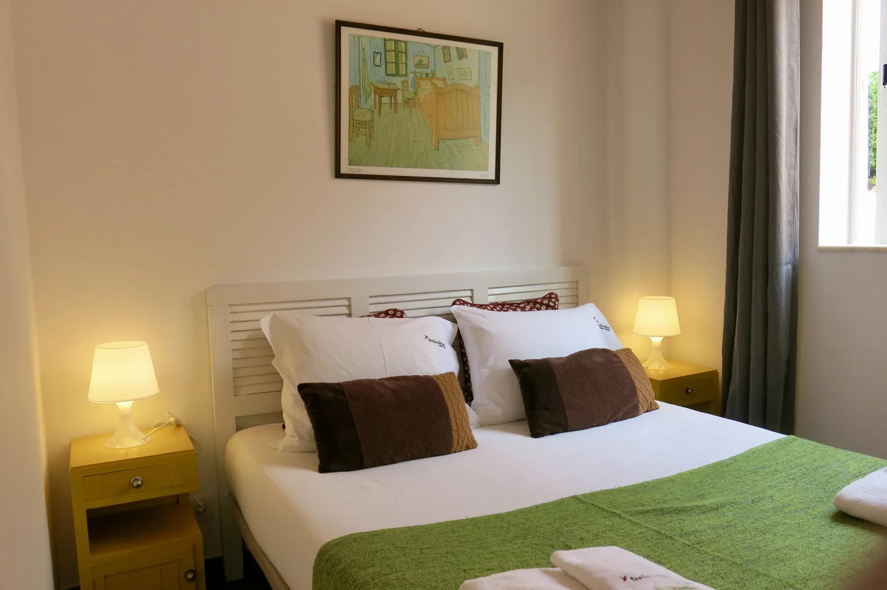 A bedroom with a double bed, bedside tables, and a framed picture above the headboard.