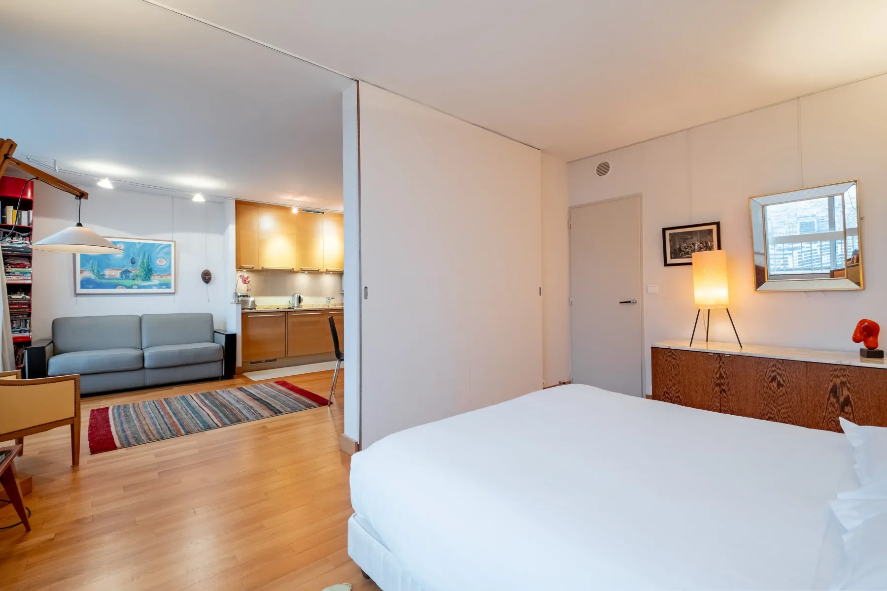 Bedroom with a bed overlooking a living area and kitchen.