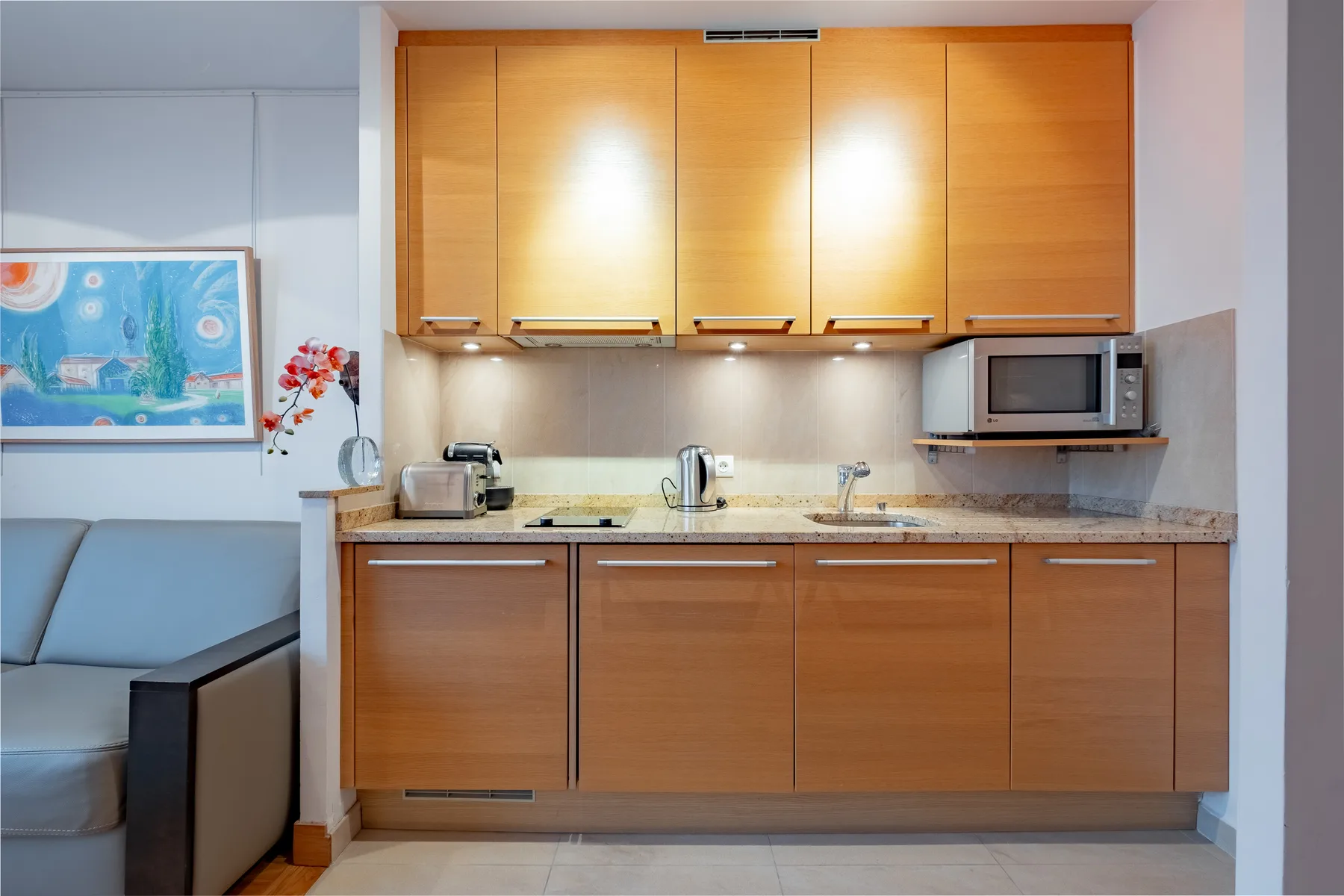 A compact kitchen with wooden cabinets, a countertop, and a microwave.
