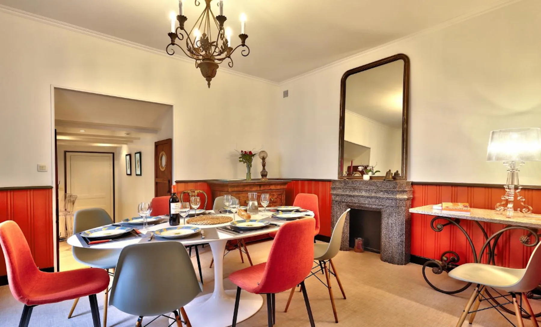 A dining room with a long table set for a meal and colorful chairs.