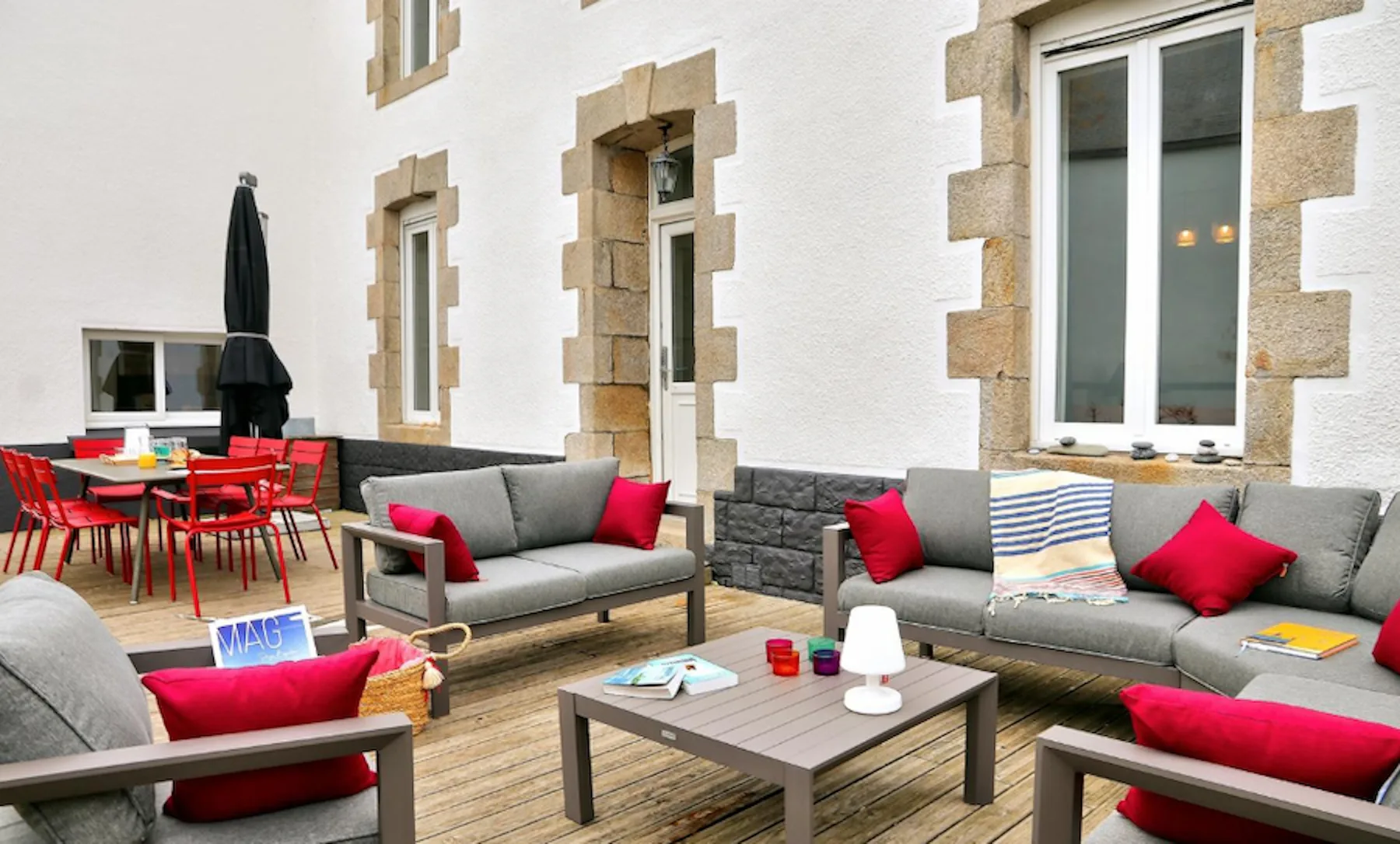 An outdoor seating area with gray sofas and a dining table.