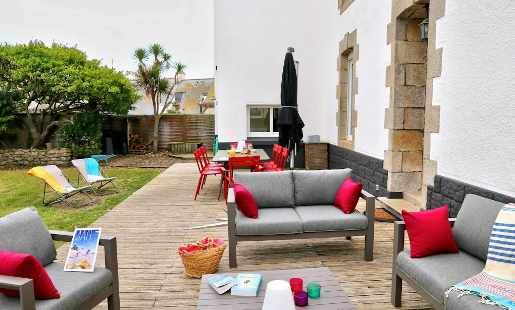 An outdoor seating area beside a house, with a table and garden chairs.