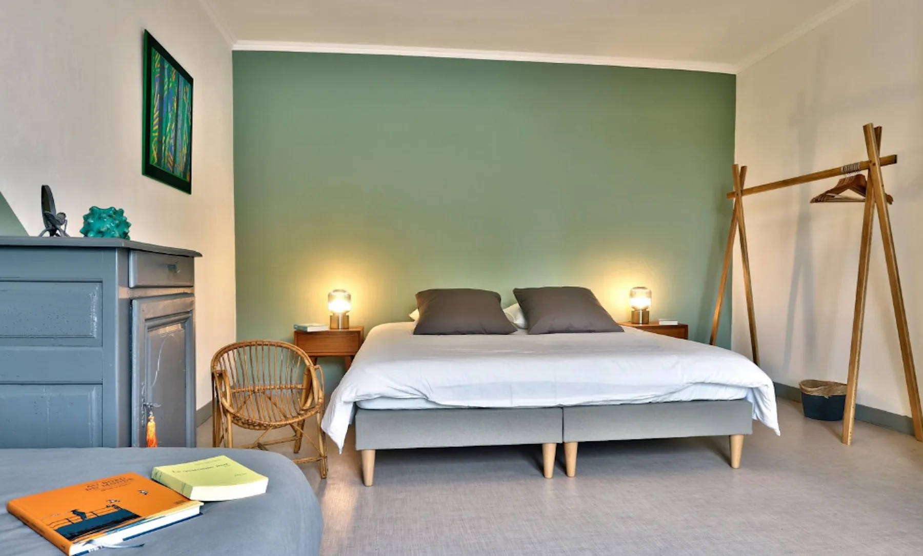 A bedroom with a bed centered against a green wall.