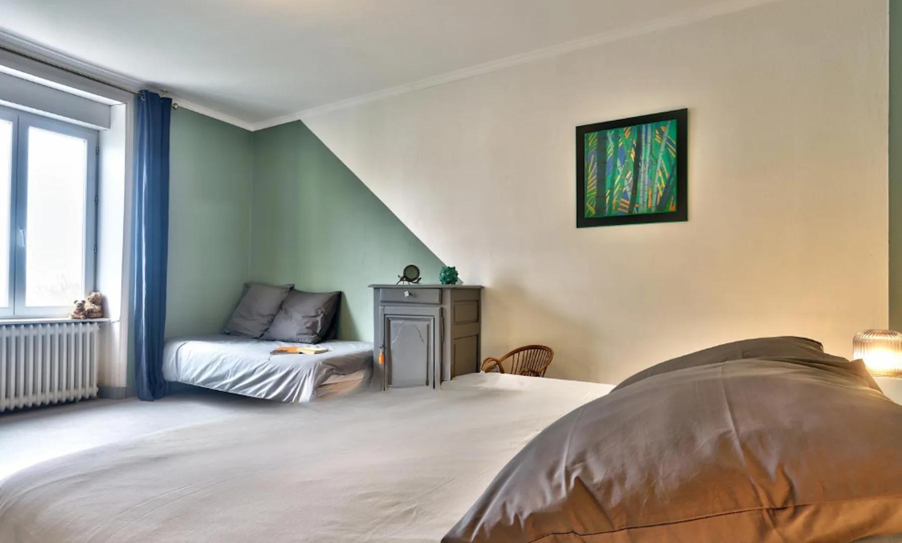 A bedroom with beds, a window, and a small cabinet.