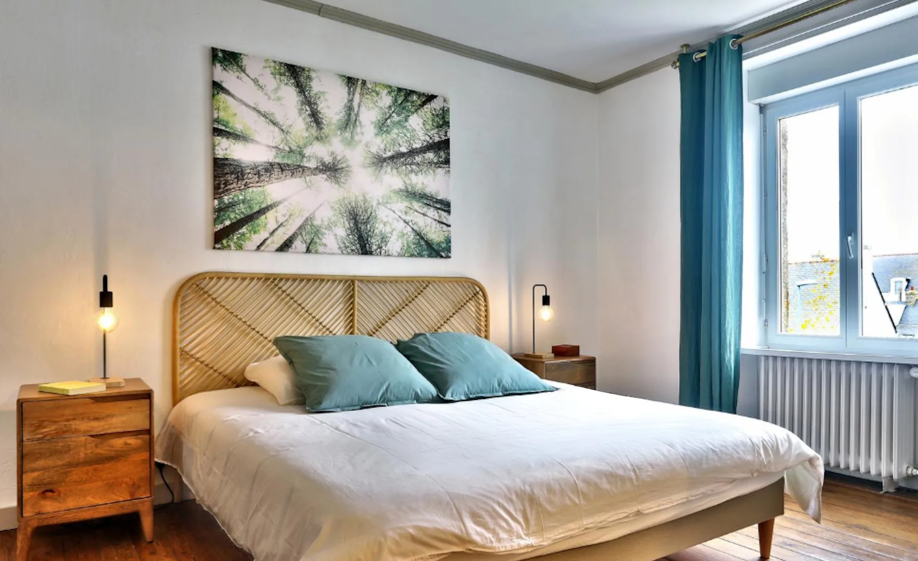 A bedroom with a bed beneath a framed nature print.