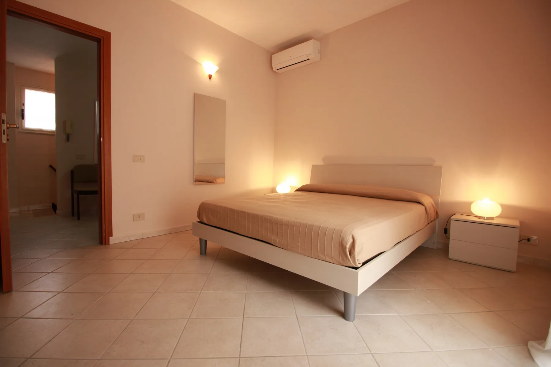 Un dormitorio con una cama, una mesita de noche y un aire acondicionado en la pared.