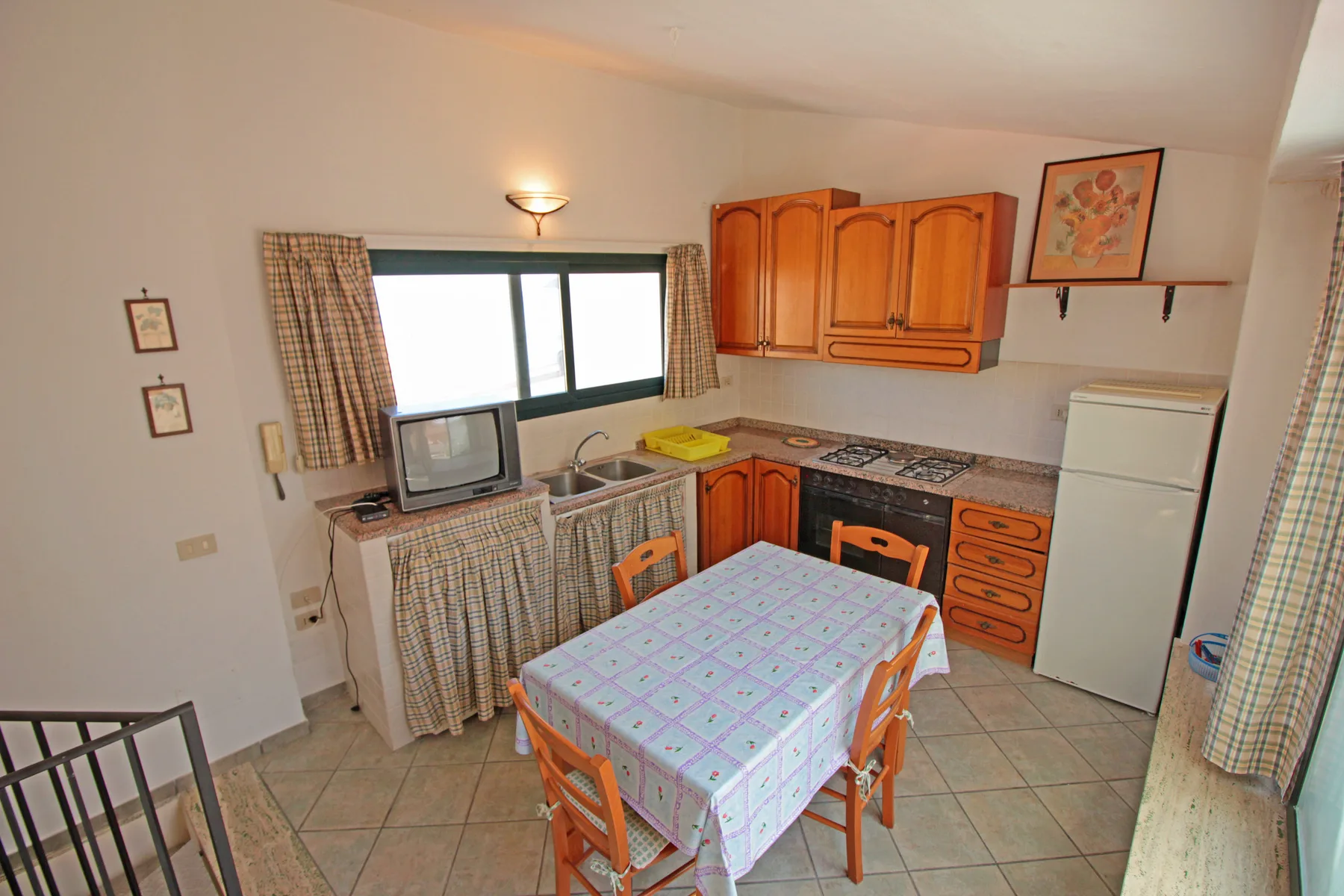 Una pequeña cocina y comedor con gabinetes de madera y una mesa.