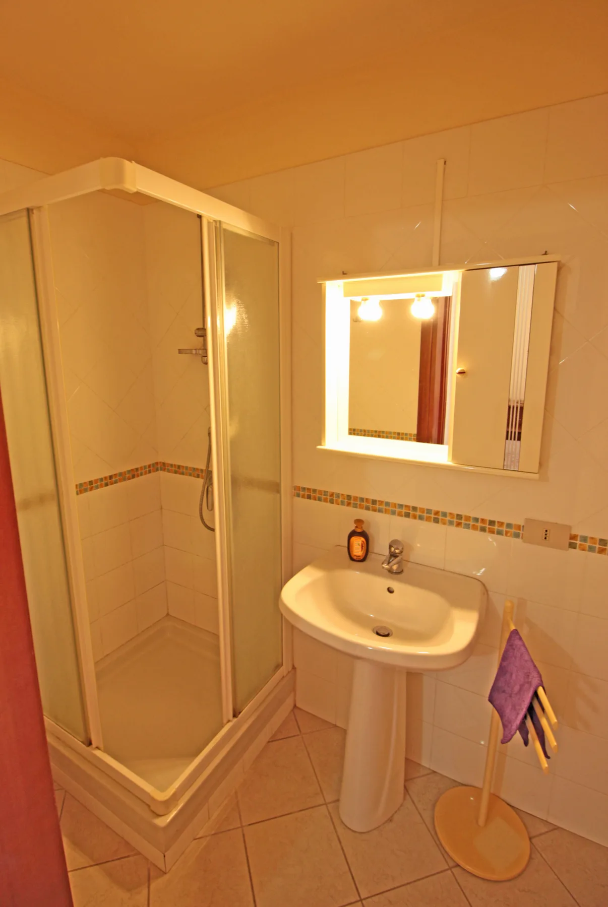 Un baño con ducha, lavabo y espejo iluminado.