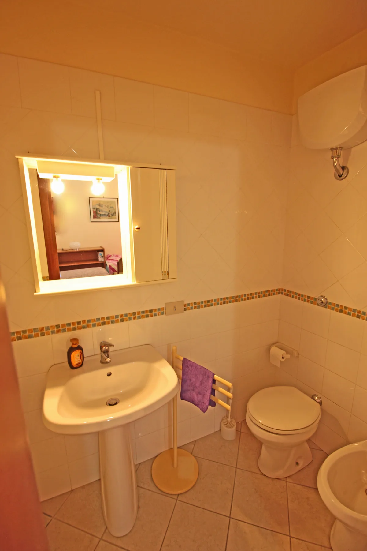 Un baño con azulejos, lavabo, espejo e inodoro.